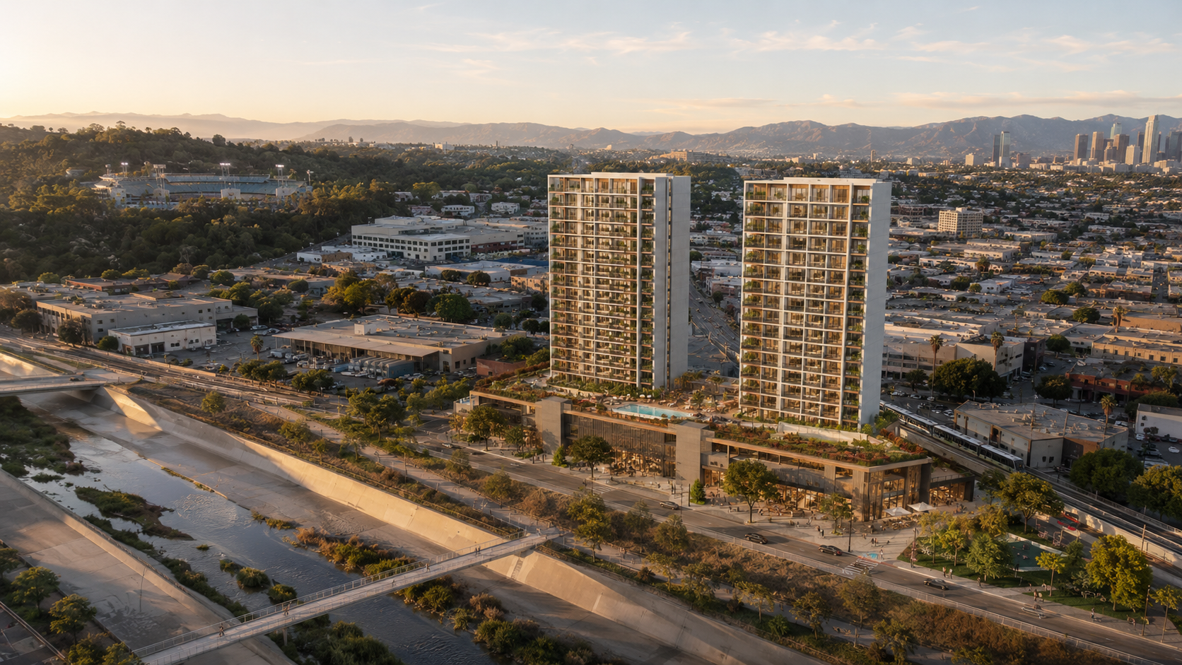 Aerial visualization of two slender residential towers over a podium on the former Lincoln Heights Jail parcel, late-afternoon light, LA River and Dodger Stadium visible in the distance.