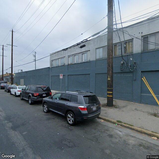 Existing-conditions street view of the Cadet Records building (5810 S Normandie Ave) — long gray-painted single-story facade with industrial-sash windows along the upper edge, parked cars along the curb.